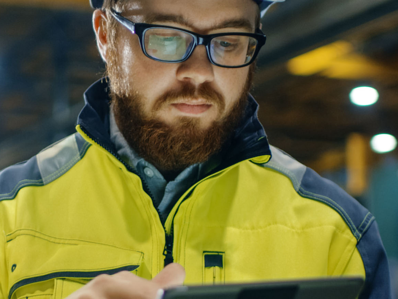 Engineer in hardhat is using a tablet computer in a heavy industry factory.
