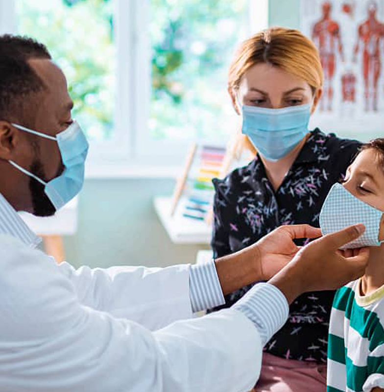 Doctor treating a young boy while the boy's mother watches