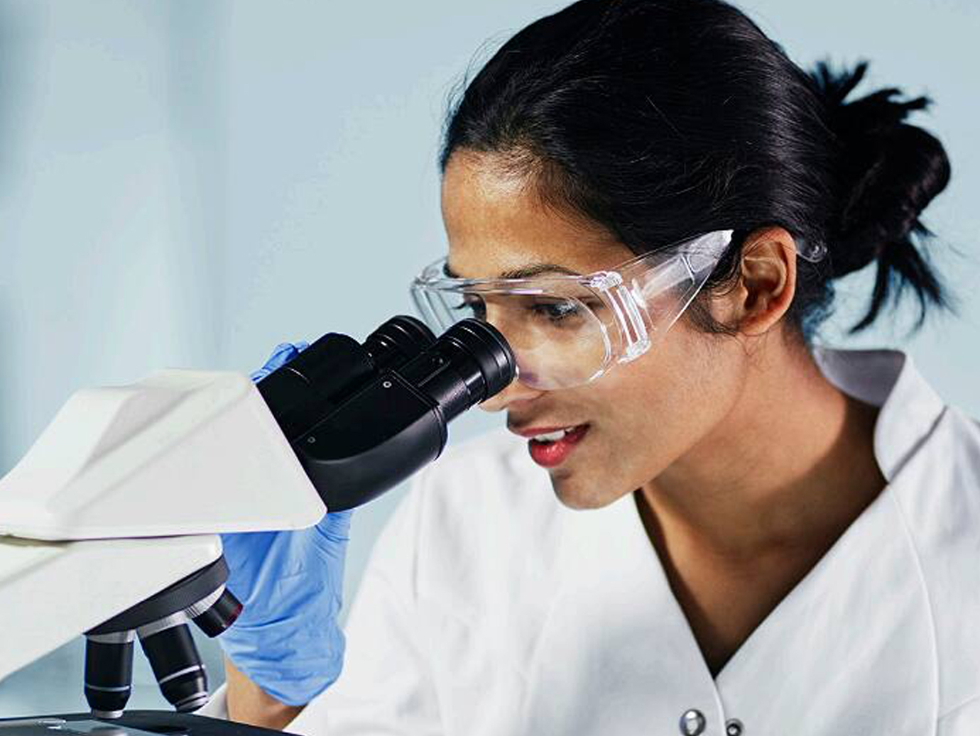 Female medical specialist looking through a microscope