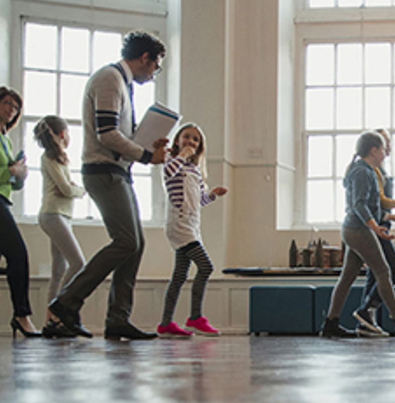 Students walking in a queue in a school hallway with their teacher walking beside them