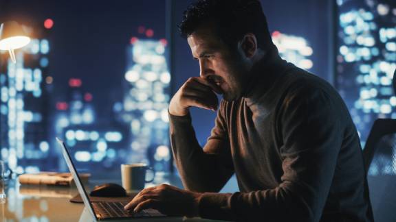 A man working at a desk with a laptop, Focused.