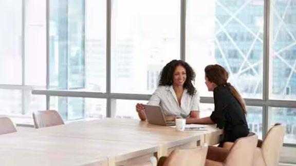 Two women sitting and discussing with laptop 