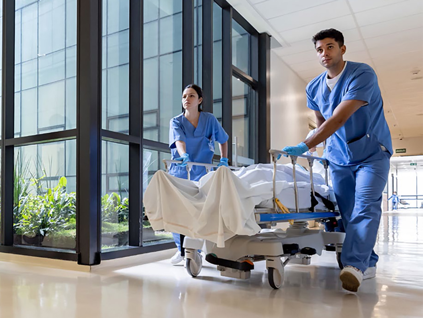Two nurses pushing a gurney with patient on it