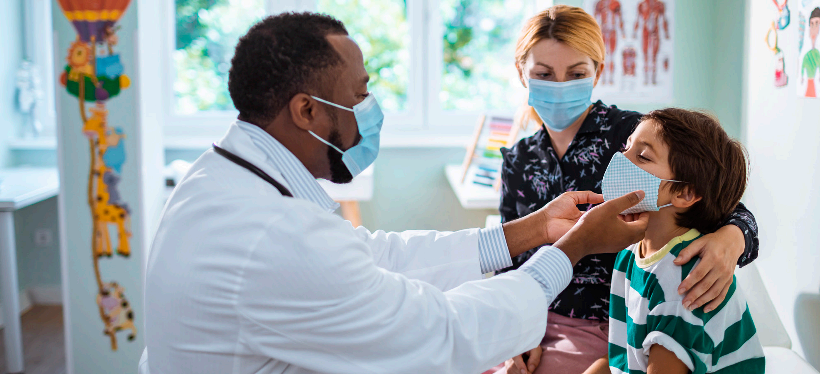 A doctor checking a small boy with his mother looking at him