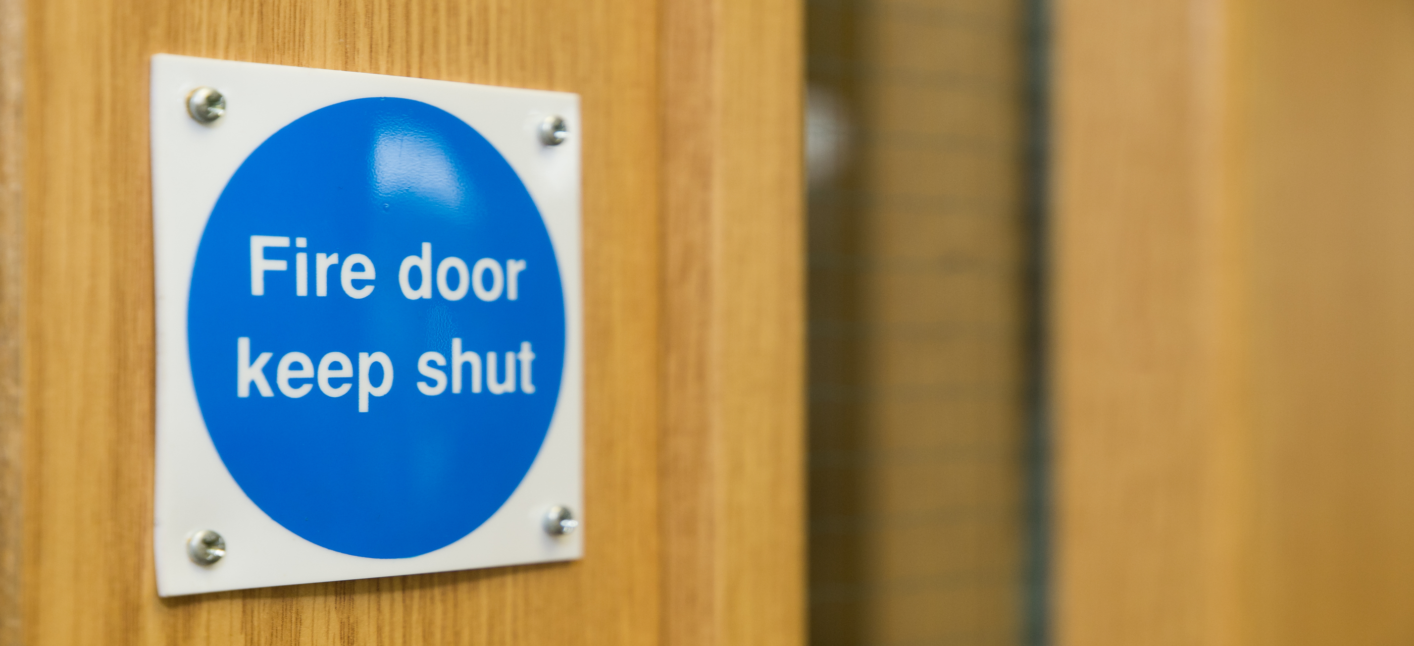 A 'Fire Door Keep Shut' sign on a wooden fire door