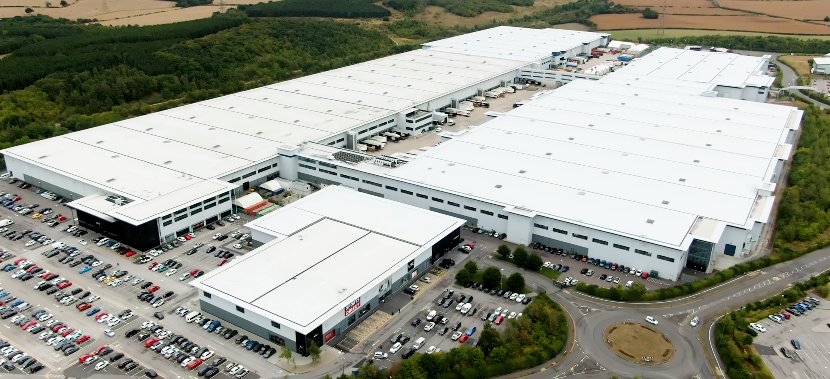A downward shot of a large warehouse with a full car park