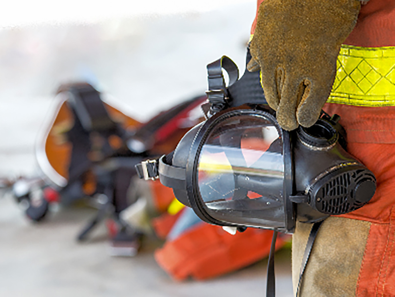 Closeup of firefighter in gear holding a gas mask