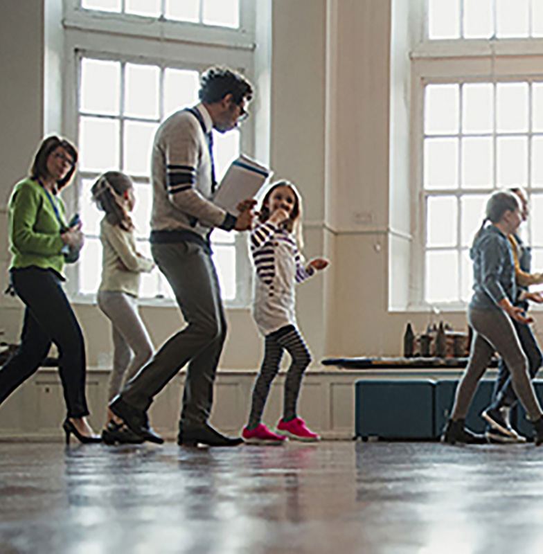 Children and teachers walking through a school assembly room