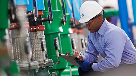 An engineer writing on a writing pad by a machine
