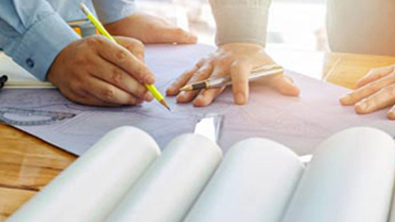 Two architects drawing up blueprints on charts