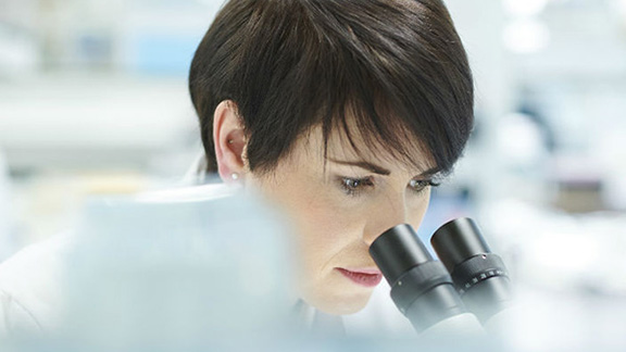 A female scientist examining a specimen using a microscope