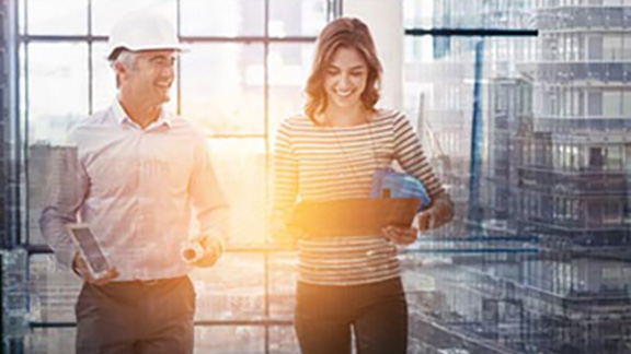 A mechanic smiling next to a woman holding a laptop