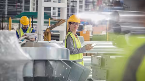 Two people in safety equipment at a factory