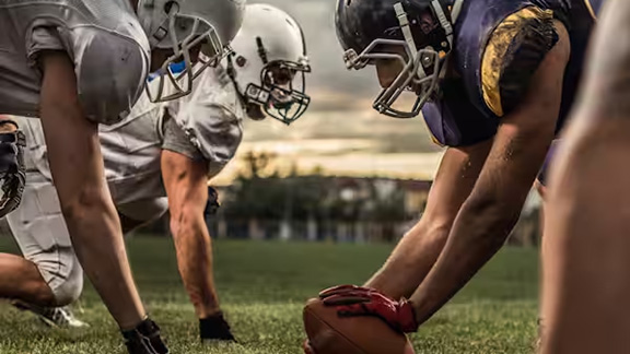 Two American football players kneeling at the field