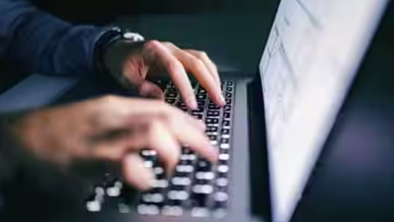Hands typing on laptop