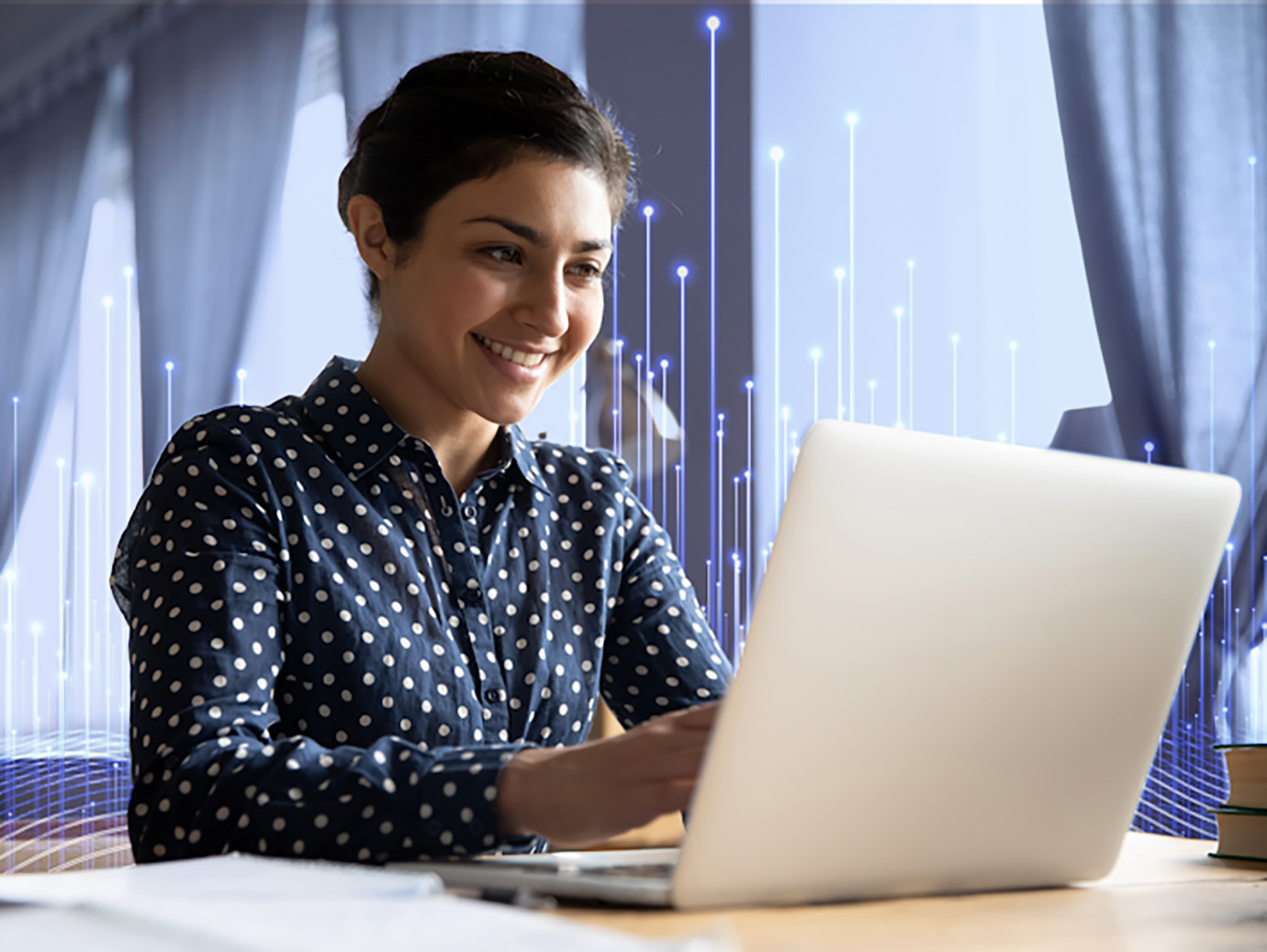 A woman smiling and working on a laptop, with OpenBlue graphics behind her 