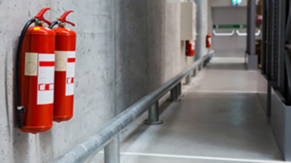 Fire extinguishers mounted on a wall along a passage