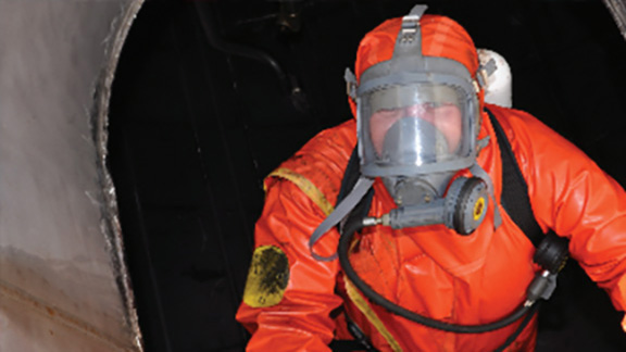 A worker in a protective suit crawling up a confined space