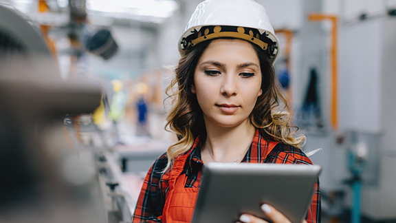 A person wearing a hard hat and holding a tablet