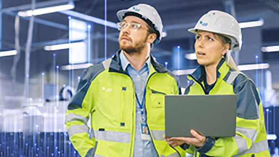 A male and a female Johnson Controls technician using a laptop, overlaid with a graphic of transmission nodes in the backgroound