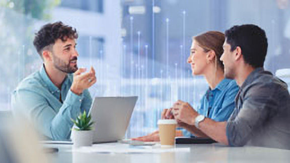 Group of employees having a friendly conversation at their desks in office