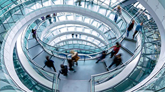 People going down a glass circular stairwell in a building
