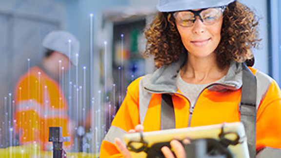 A female maintenance engineer looking a tablet, with OpenBlue graphics overlaid behind