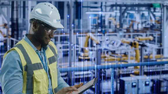 A maintenance worker scrolling on a tablet, with OpenBlue graphics in the background
