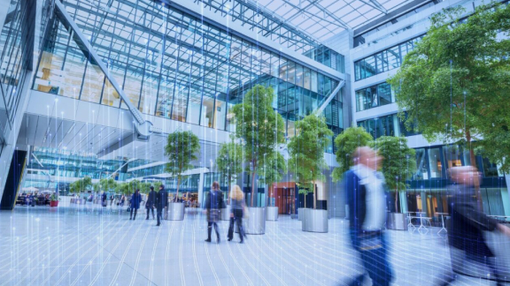 People walking along an atrium of an office building, overlaid with OpenBlue graphics
