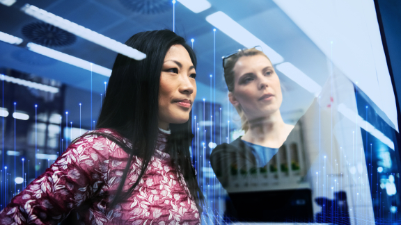 Two women looking through a window, with OpenBlue graphics in the foreground