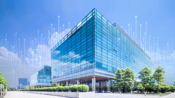 A glass commercial building at daytime, overlaid with OpenBlue graphics in the background