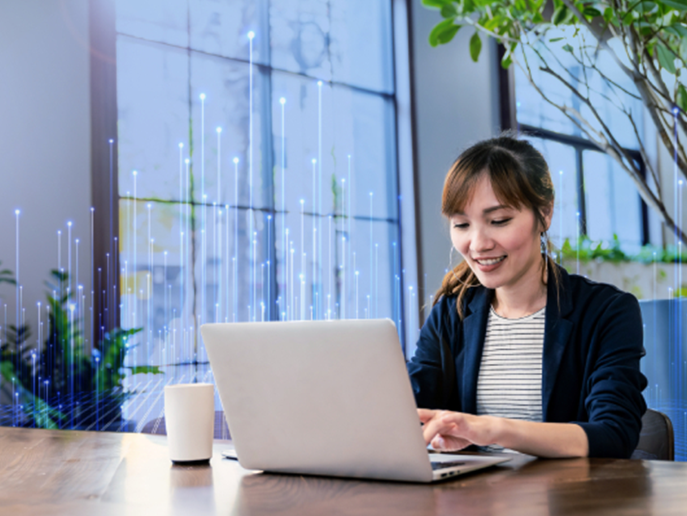 A woman smiling as she works on her laptop in an office, surrounded by OpenBlue graphics
