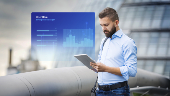 A man standing and looking at a tablet, with a blue OpenBlue poster overlaid in the middle