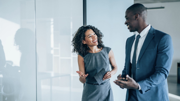 A man and a woman engaged in friendly conversation in an office